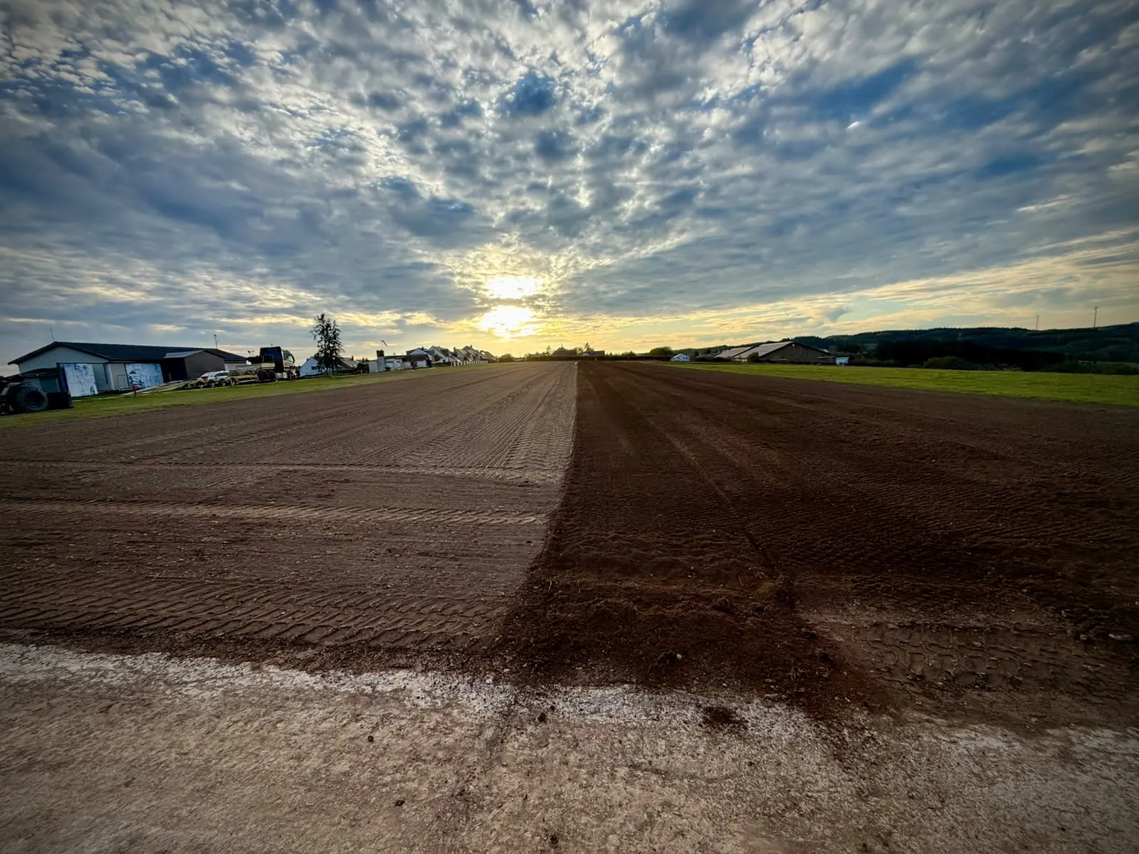 The prepared bare-earth runway looking straight towards the hangars and village at sunset